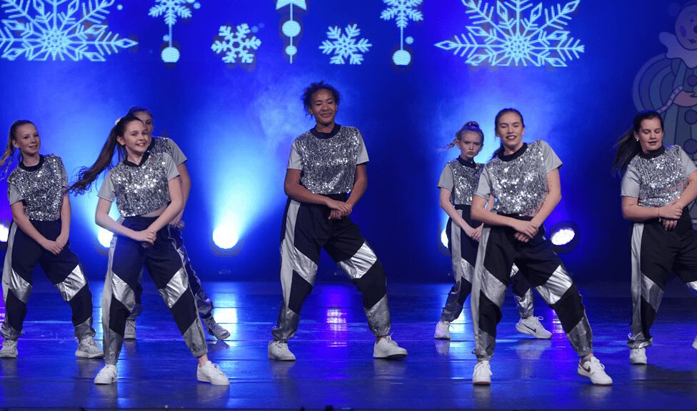 Youth dance crew in silver tops under snowflakes