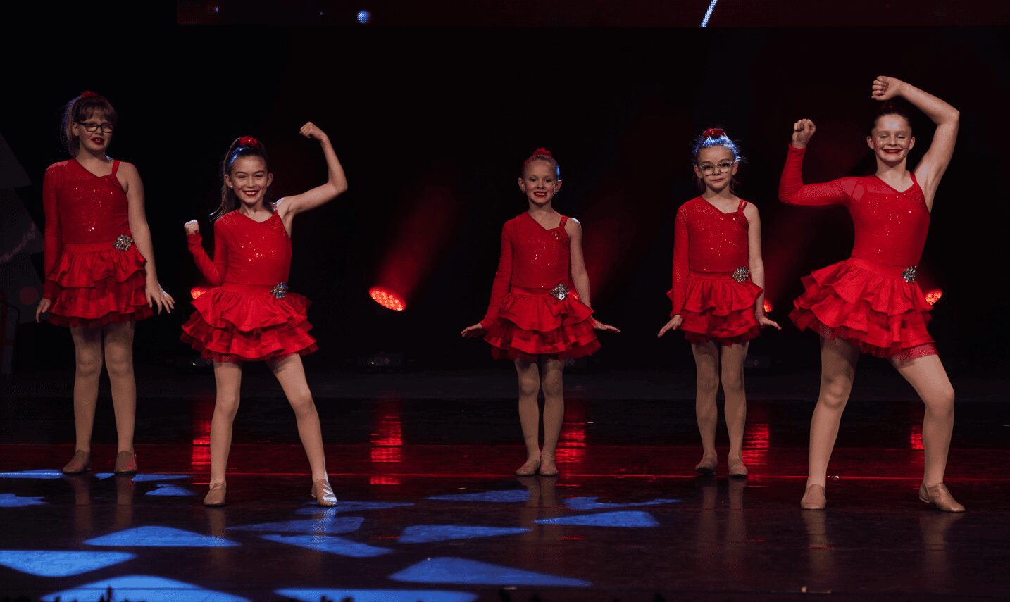 Young performers in sparkling red ruffled costumes